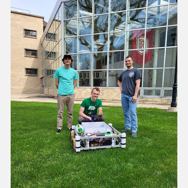Bradley students posing in front of lawn care robot.