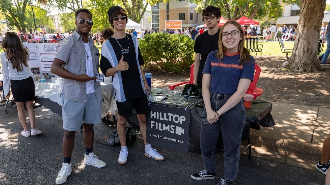 Students at the Bradley Activities Fair explore the student organizations on campus, with some posing in front of the Hilltop Films table.