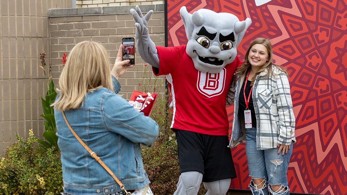 A perspective student stops and poses for a photo with Kaboom!, Bradley's gargoyle mascot.
